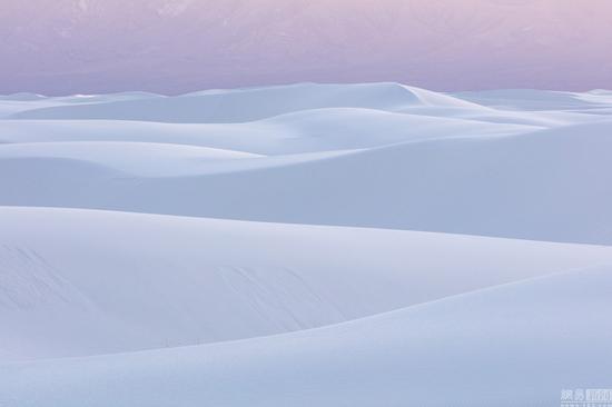 当地时间2016年3月,美国,摄影师David Clapp走访亚利桑那州、犹他州、内华达州和新墨西哥州拍摄美国西南部的沙漠荒地,看起来像外太空景观十分惊艳。图为当地时间2016年3月,美国亚利桑那州,一男子晚间站在岩石上拿着手电筒照向银河系。