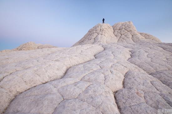 当地时间2016年3月,美国,摄影师David Clapp走访亚利桑那州、犹他州、内华达州和新墨西哥州拍摄美国西南部的沙漠荒地,看起来像外太空景观十分惊艳。图为当地时间2016年3月,美国亚利桑那州,一男子晚间站在岩石上拿着手电筒照向银河系。