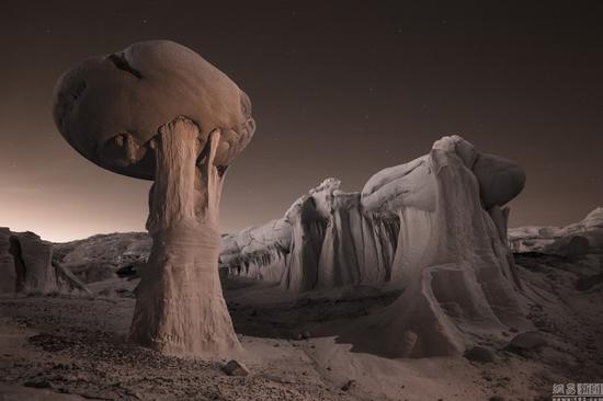 当地时间2016年3月,美国,摄影师David Clapp走访亚利桑那州、犹他州、内华达州和新墨西哥州拍摄美国西南部的沙漠荒地,看起来像外太空景观十分惊艳。图为当地时间2016年3月,美国亚利桑那州,一男子晚间站在岩石上拿着手电筒照向银河系。